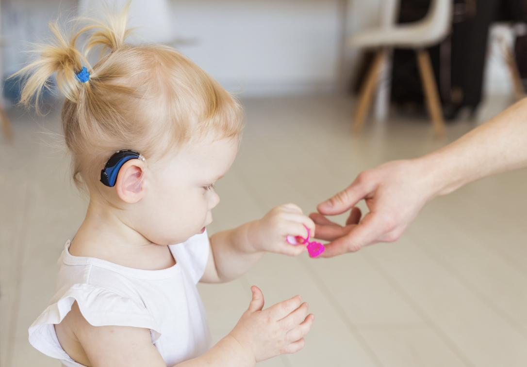 Child with cochlear implant reaching for toy Child with cochlear implant reaching for toy